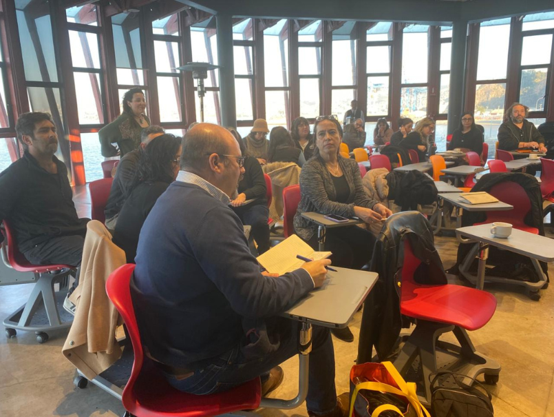 Profesores de PIFP desarrollan actividad en sus asientos. Un profesor está leyendo desde su cuaderno.