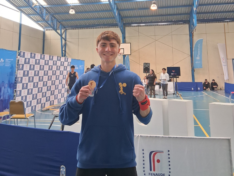 Felipe Armijo sonriendo y sosteniendo medalla. 